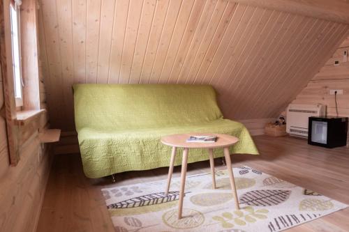 a small room with a green bed and a table at Sodyba Namelis medyje Anykščiuose in Anykščiai