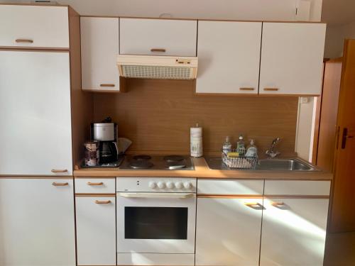 a kitchen with white cabinets and a stove top oven at Einladendes Appartement im Grünen für 2 Personen in Ostrach
