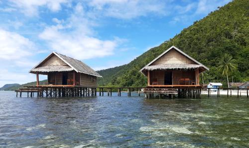 deux cabanes sur pilotis dans une masse d'eau dans l'établissement Frances Homestay - Raja Ampat, à Pulau Mansuar