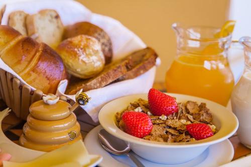 Una mesa de desayuno con un tazón de cereales y fresas. en Montinho De Ouro, en Luz
