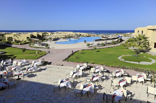 a group of chairs sitting on a patio with a pool at Three Corners Fayrouz Plaza Beach Resort in Port Ghalib