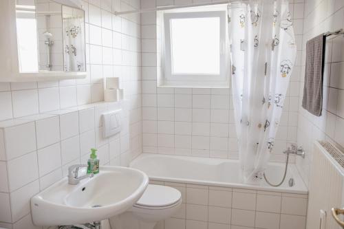 La salle de bains blanche est pourvue d'un lavabo, de toilettes et d'une baignoire. dans l'établissement Stilvolle 2 Schlafzimmer Apartments Heidegarten, Osterheide, Zentrum, à Schneverdingen