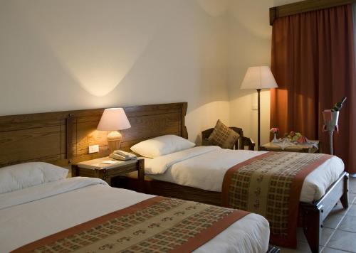 a hotel room with two beds and a chair at Three Corners Fayrouz Plaza Beach Resort in Port Ghalib