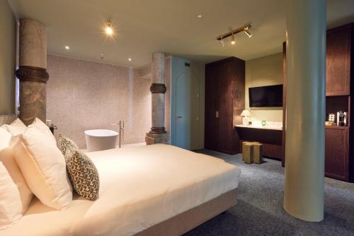 a bedroom with a large bed and a bathroom at Heavens Hotel in Hoorn