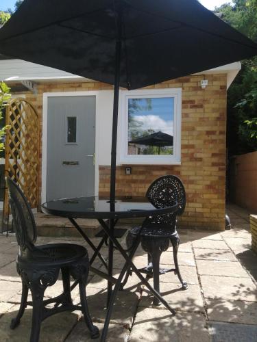 a black table and two chairs with an umbrella at Quest Fulfiller - Near General Hospital, Free Parking & Garden in Southampton