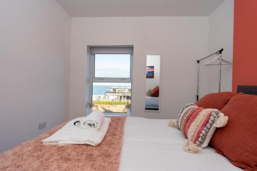 1 dormitorio con cama blanca y ventana en Sea Views Modern Two Bedroom Apartment en Lowestoft