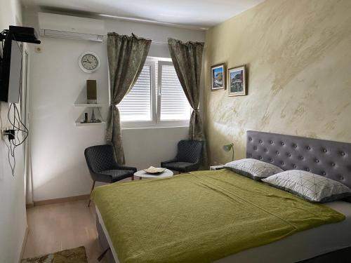 1 dormitorio con 1 cama verde y 2 sillas en CITY Lux Apartment, en Podgorica