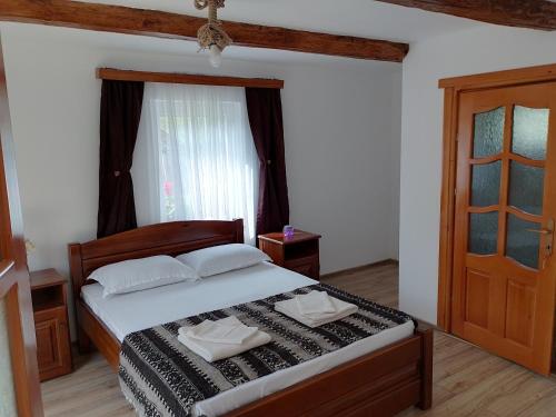 a bedroom with a bed and a window and a door at Wild-Traditional Bucovina in Câmpulung Moldovenesc