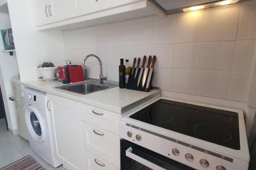 a white kitchen with a sink and a stove at The Olive Tree Villa Lindos in Líndos