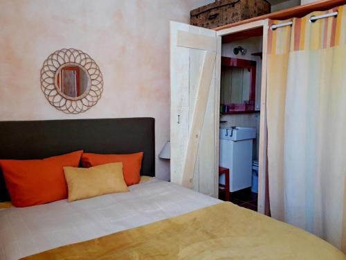 a bedroom with a bed with orange pillows and a mirror at Chambre d'hôte Farniente in Aigues-Mortes
