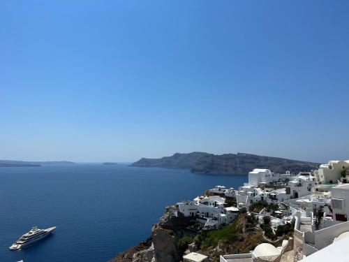 a group of white buildings on a hill next to the water at Imerti Suites in Oia