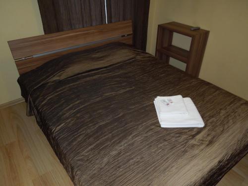 a bed with a wooden head board with a white towel on it at Motel Sapnis in Jēkabpils