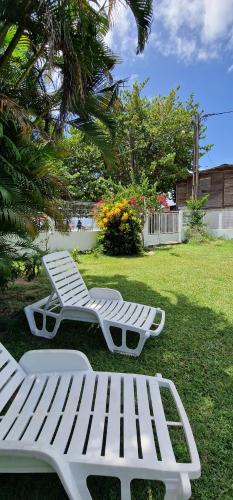 two white lounge chairs sitting in the grass at villa marie eugenie in Les Trois-Îlets