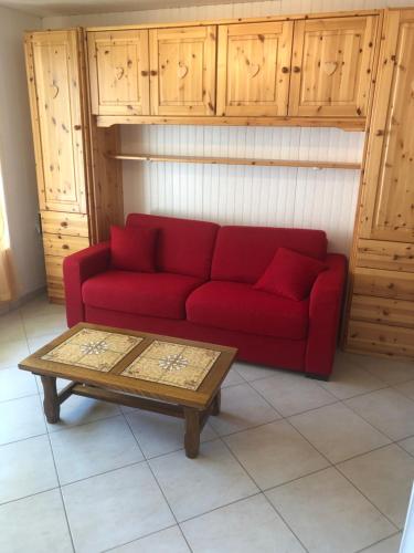 un divano rosso in soggiorno con tavolino di Studio Les Carroz a Les Carroz d'Araches