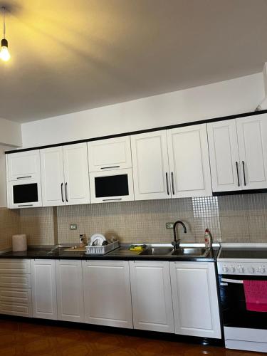 eine Küche mit weißen Schränken und einer Spüle in der Unterkunft Appartamento incantevole con posto auto privato in Vlorë