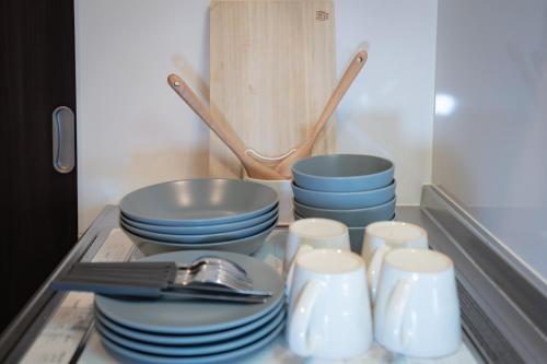京都市にあるINA HOUSE Nijojoのキャビネットの中に積み重ねられた皿やボウル、食器類
