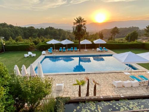 - une piscine avec des chaises et des parasols et le coucher du soleil dans l'établissement Quinta do Paço Hotel, à Vila Real