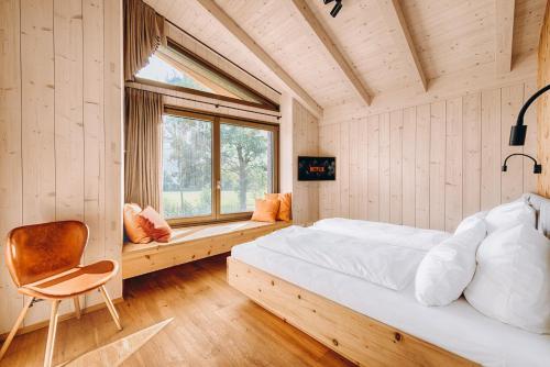 ein Schlafzimmer mit einem Bett, einem Stuhl und einem Fenster in der Unterkunft Chalet Dreitorspitz - Riverside in Garmisch-Partenkirchen