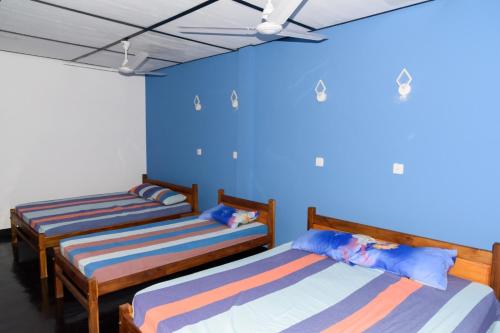 2 camas en una habitación con paredes azules en Gnanam Holiday Inn en Pasikuda