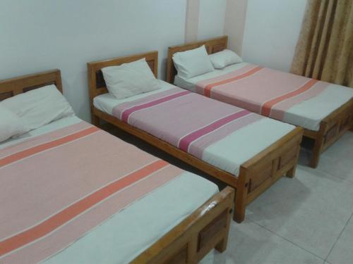 two twin beds in a room with at Gnanam Holiday Inn in Pasikuda