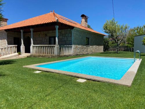 a swimming pool in front of a house at Giesteira's House in Arcos de Valdevez