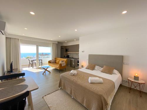 a bedroom with a large bed and a living room at Estúdio com Fantástica Vista Mar - Praia da Luz in Luz
