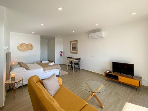 a hotel room with a bed and a couch and a tv at Estúdio com Fantástica Vista Mar - Praia da Luz in Luz