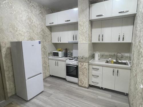 una cucina con armadietti bianchi e frigorifero bianco di Appartement Kholova a Dushanbe