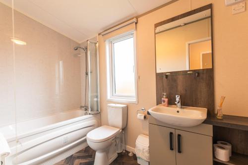 a bathroom with a white toilet and a sink at Bella Rose Lodge with Hot Tub in Malton