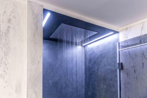 a bathroom with a shower with a blue wall at VIA DELLA SPIGA N50 - Luxury Loft in the Heart of the Fashion District in Milan