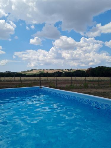 a swimming pool in the middle of a field with a blue sky at Agriturismo IL Paradiso di Berignone in Caprareccia