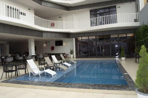 a hotel with a swimming pool with chairs and tables at AXIL HÔTEL in Dakar
