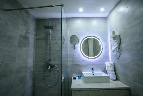 een badkamer met een douche, een wastafel en een spiegel bij Suites Hôtel Les Charmilles & Spa in La Marsa
