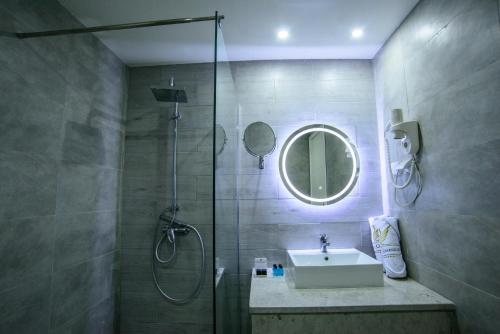 a bathroom with a shower and a sink and a mirror at Suites Hôtel Les Charmilles & Spa in La Marsa