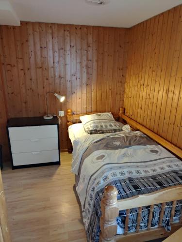 Cœur du Valais, à 4 mn du centre de Crans-Montana في كرانس مونتانا: غرفة نوم بسرير مع جدار خشبي