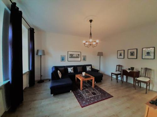 a living room with a black couch and a table at Ferienwohnung-Stricker-Bad-Sachsa in Bad Sachsa