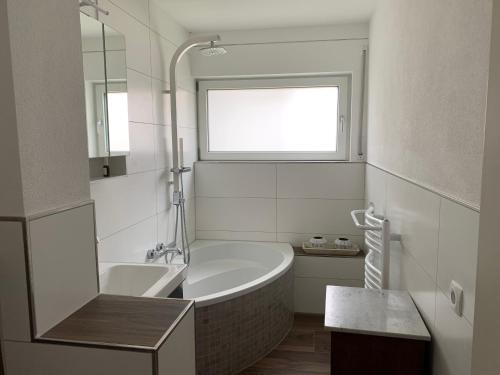 a white bathroom with a tub and a window at Helle Wohnung mit Wintergarten, Terrasse und Garten in Bad Liebenzell