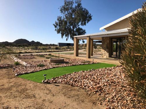 a house with a lawn in front of a building at Daberas Guest Farm in Augrabies