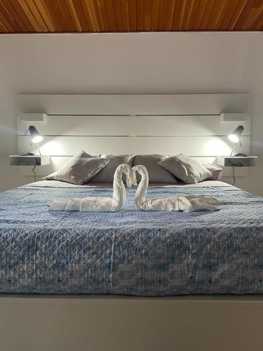 a bed with two swans made to look like hearts at The White Sail - Mondello Apartment with Terrace - casa di vincenzo e andrea in Mondello