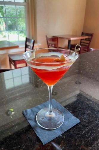 una bebida en un vaso de martini sobre una mesa en The Woodford Inn en Versailles