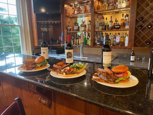 tre piatti di cibo in un bar con bottiglie di vino di The Woodford Inn a Versailles