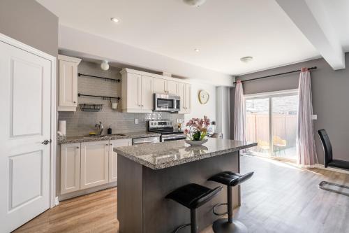 a kitchen with white cabinets and a counter with stools at GlobalStay Waterfront 5 Bedroom Townhouse Hot tub Sauna Stoney Creek in Hamilton