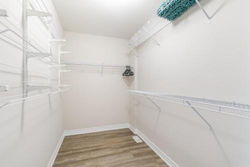 a walk in closet with white walls and glass shelves at GLOBALSTAY Waterfront 20Ppl 5 Bedroom Townhouse Hot tub Sauna in Hamilton