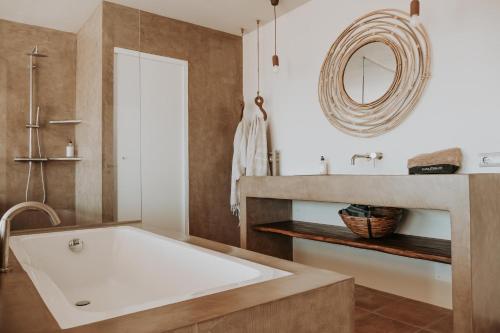 uma casa de banho com uma grande banheira branca e um lavatório. em Casa Stellar - boutique villa with private heated pool and sea view - sustainably solar powered em San Jose de sa Talaia