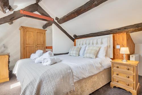 um quarto com uma cama grande com lençóis brancos e almofadas em Cottage 1, Old Farmhouse Mews em Braithwaite