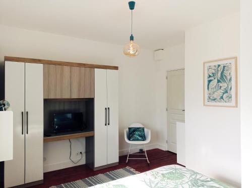 亞眠的住宿－Irziana - Au jardin d'Henriville，卧室配有白色橱柜、床和电视。