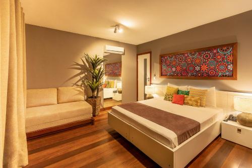 a bedroom with a bed and a couch at Bravo Pousada Design in Cabo Frio