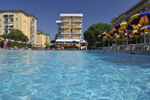 una grande piscina con sedie e ombrelloni di Hotel Bellevue a Bibione