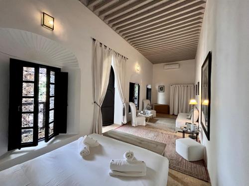 RIAD ENNAFOURA BOUTIQUE HOTEL في مراكش: غرفة نوم بسرير ابيض وغرفة معيشة