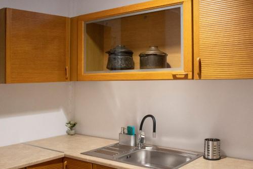 una cocina con fregadero y 2 ollas en un estante en Hara's Studio en Perdhika